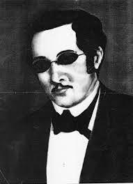 Fotográfica em preto e branca com José Álvares que era um homem, com cabelos curtos, usava um bigode e óculos. 