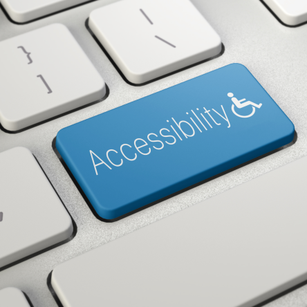 Fotografia de teclado de computador branco, com uma tecla azul em destaque, que está escrita "Acessibilidade" e, ao lado, um símbolo da pessoa com deficiência física.