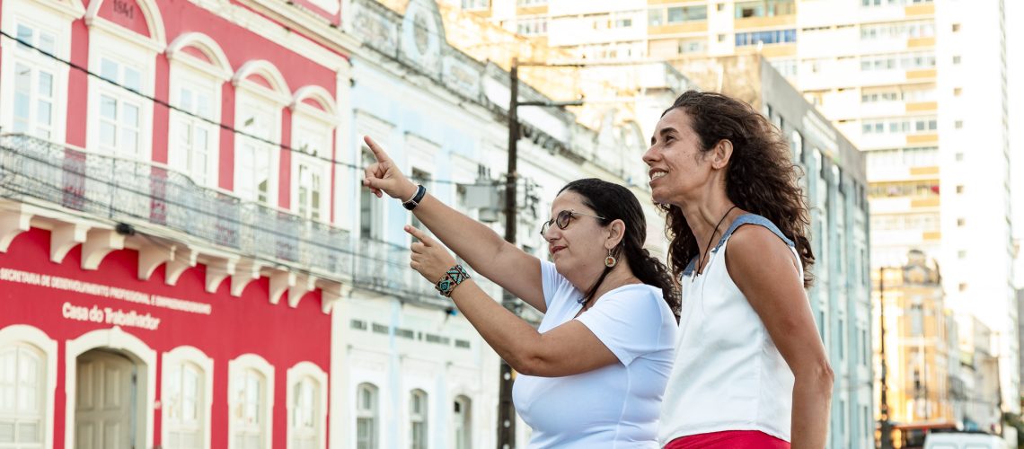 Fotografia de duas mulheres observando os casarões coloridos da Rua da Aurora.